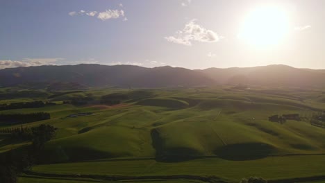 drone flight towards the setting sun above soft rolling hills at the foothills of new zealand's southern alps