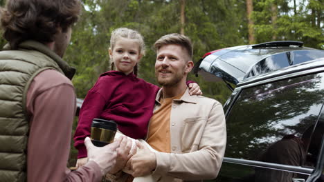 family outside big black car before travelling