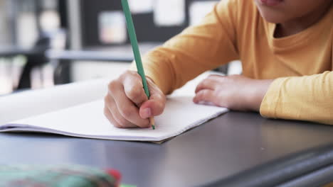 en un entorno escolar, un joven estudiante biracial se centra en escribir