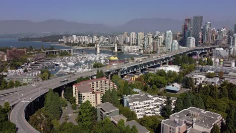 aerial hold granville island bridge leading into the downtown vancouver false creek headed into yaletown english bay the main city core with a bg foggy horizon of north west vancouver mountains 2-2