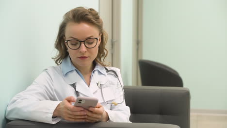 pretty female doctor texting on mobile phone at clinic