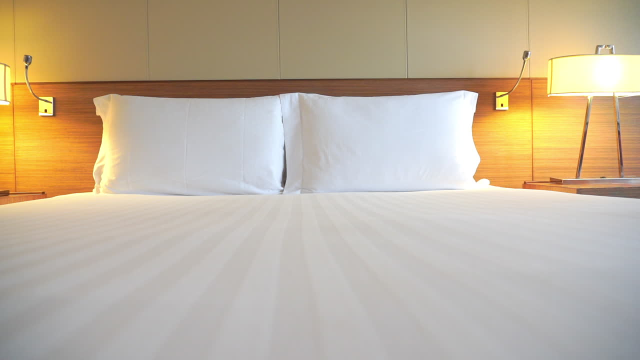 호텔 스위트룸 침대 발치에 있는 카메라가 가장자리를 가로질러 이동합니다.