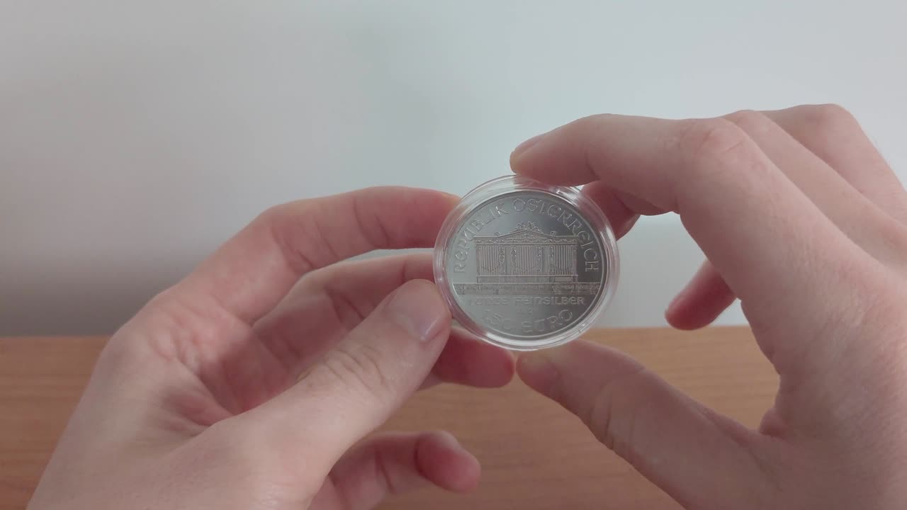 el reloj en la mano es una moneda de plata de la filarmónica de viena, una moneda de 1,5 euros.