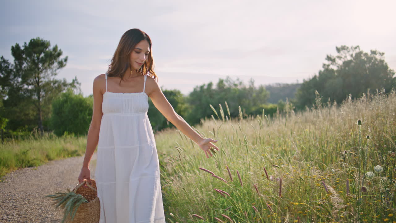 Romantic woman strolling countryside touching spikelets at meadow. Girl walking