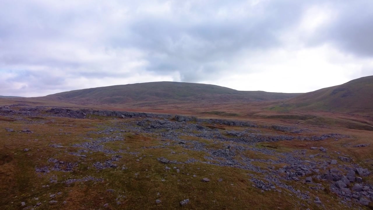 Einführende Luftaufnahme über felsigem, zerklüftetem Gelände im Brecon Beacons Nationalpark in Wales mit dunklem, bewölktem Himmel 4K.