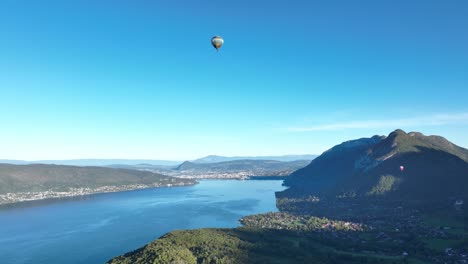 hot air balloon flying low over annecy lake in a summer morning