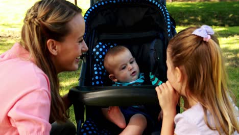 mother and daughter playing with baby in a pram in the park