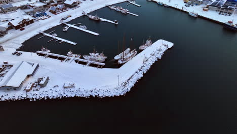 boats are moored in the icelandic port of husavik in a winter landscape on a cloudy day