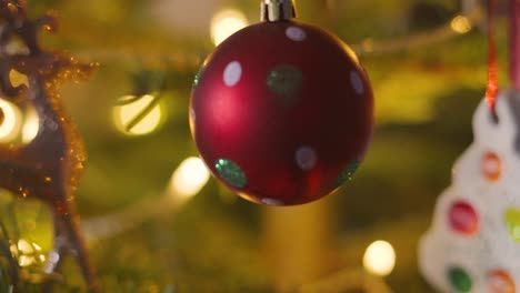 close up sliding shot of decorated christmas fir tree bourballs and small hanging ornaments with xmas lights on branches. holidays festive seasonal footage 4k video background.