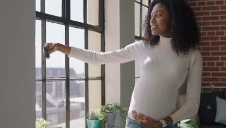 mujer afroamericana embarazada feliz usando un teléfono inteligente tomando fotos selfie compartiendo el estilo de vida de la maternidad en las redes sociales sonriendo posando para la cámara del teléfono móvil en un apartamento