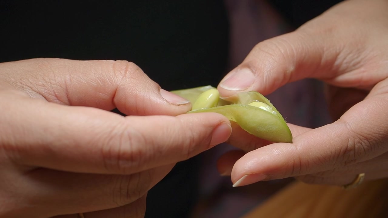 Close-up of Hands Peeling Fresh Edamame Pods