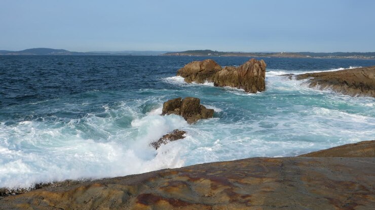 Paesaggio marino con onde impetuose che si infrangono sulla costa rocciosa, giornata soleggiata, SLOMO