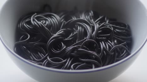 hot steaming black pasta in a white bowl