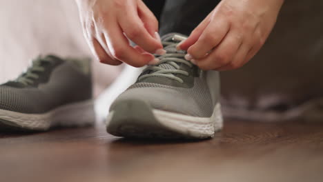 mujer aprieta los cordones de las zapatillas de deporte de primer plano. mujer deportiva enérgica se pone zapatos deportivos para correr en el club de fitness en cámara lenta. estilo de vida saludable