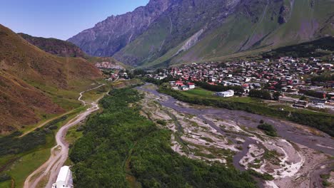 aerial of georgian remote settlement in valley with glacial stream meandering and creation flowing patterns