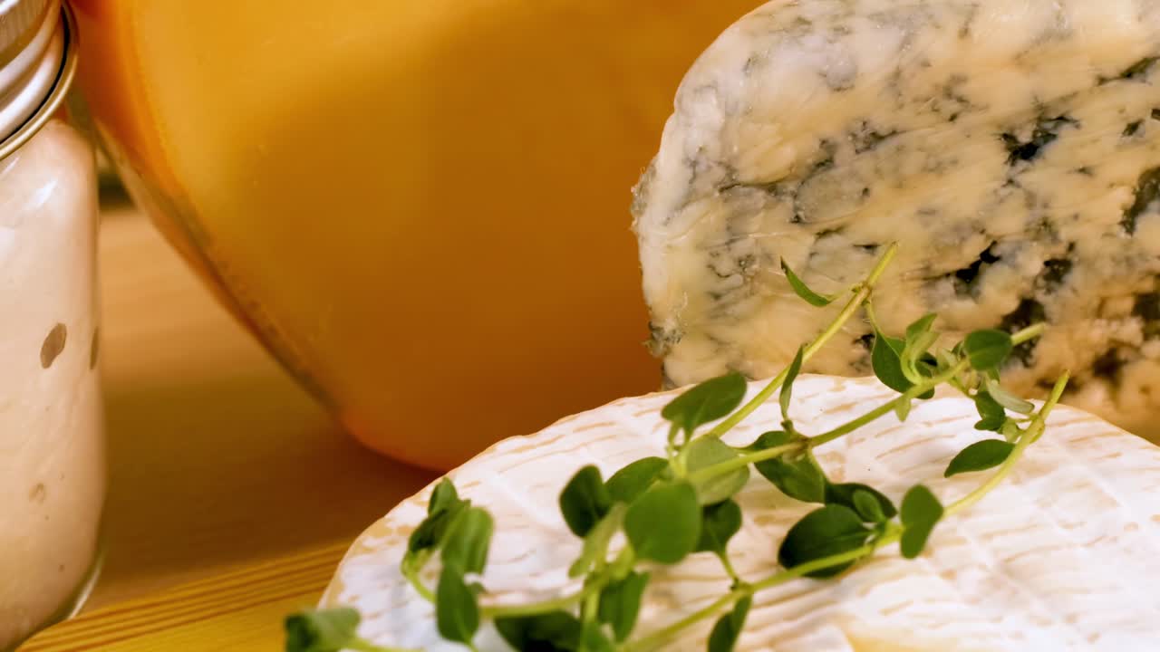 A variety of cheeses displayed with fresh herbs, highlighting texture and artisanal quality.