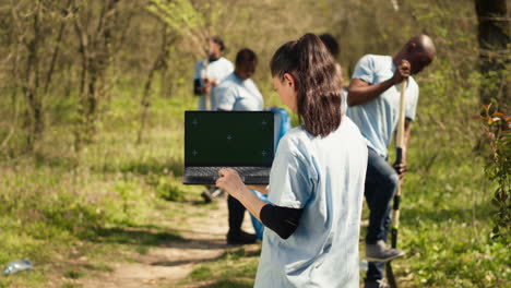 environmental conservation volunteer holds a greenscreen laptop