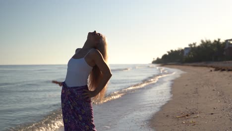 Pretty-mature-woman-on-a-beach-raises-her-arms-and-turns-around-with-emotion-of-freedom