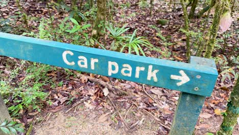 a wooden sign directs visitors to a car park amidst lush greenery, captured in natural daylight