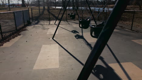 empty toddler swing set in park, winter time