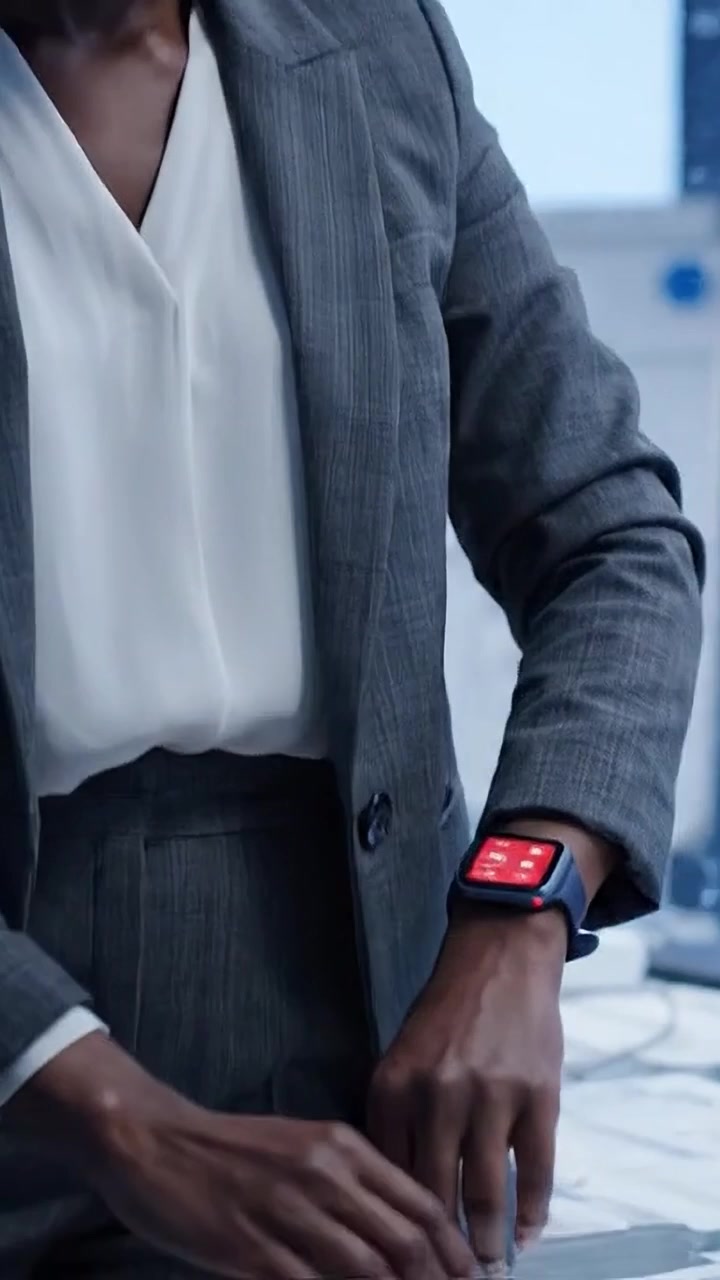Focused Business Professional Checking Smartwatch While Reviewing Papers in Modern Office Environment, Demonstrating Productivity and Time Management Skills