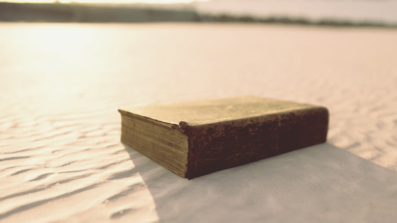 Vecchio libro appoggiato sulla sabbia soffice sotto la calda luce del sole nelle ore pomeridiane