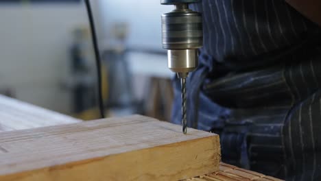 carpenter drilling wooden plank with machine in workshop 4k