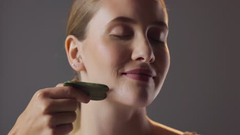 woman doing face massage with gua sha