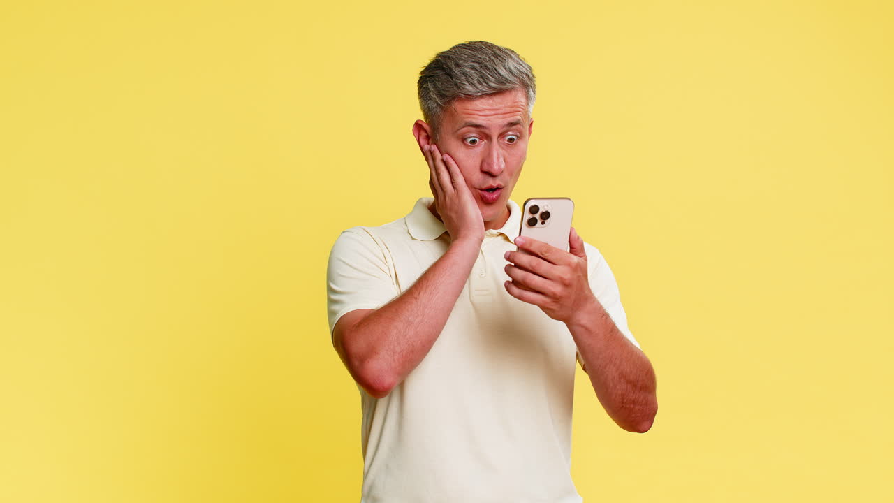 Hombre desplazándose por su smartphone, de repente se sorprende con los ojos muy abiertos y la boca abierta, impactado por noticias inesperadas.