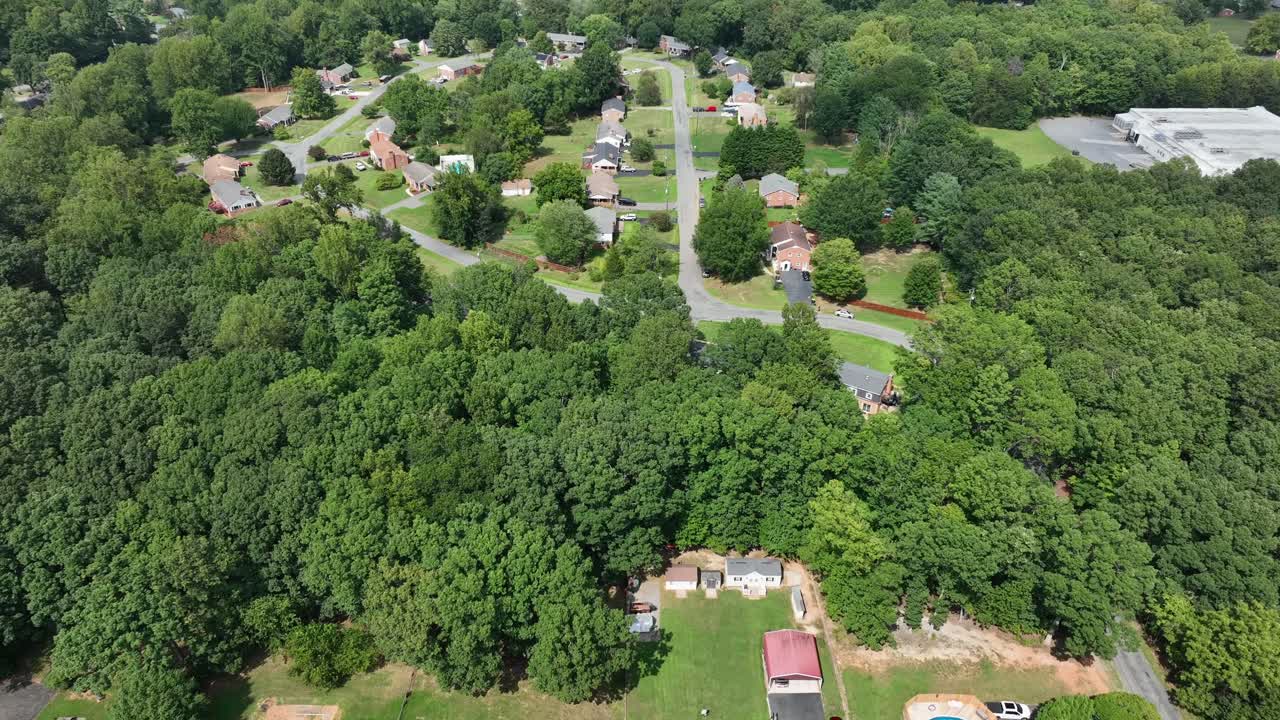 Slow drone flight over well-kept American neighborhood during sunny day in summer. Suburb district with American houses, solar panels on roof and swimming pool. Flyover shot. Virginia state in USA