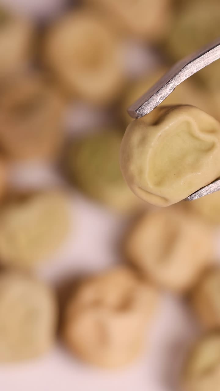 Primo piano di pinzette che tengono semi su un piatto, mettendo in risalto la consistenza e i dettagli sotto una luce soffusa.