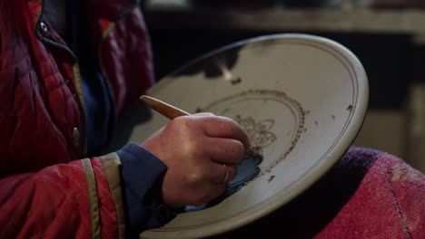 old woman making decoration on wet clay product in pottery