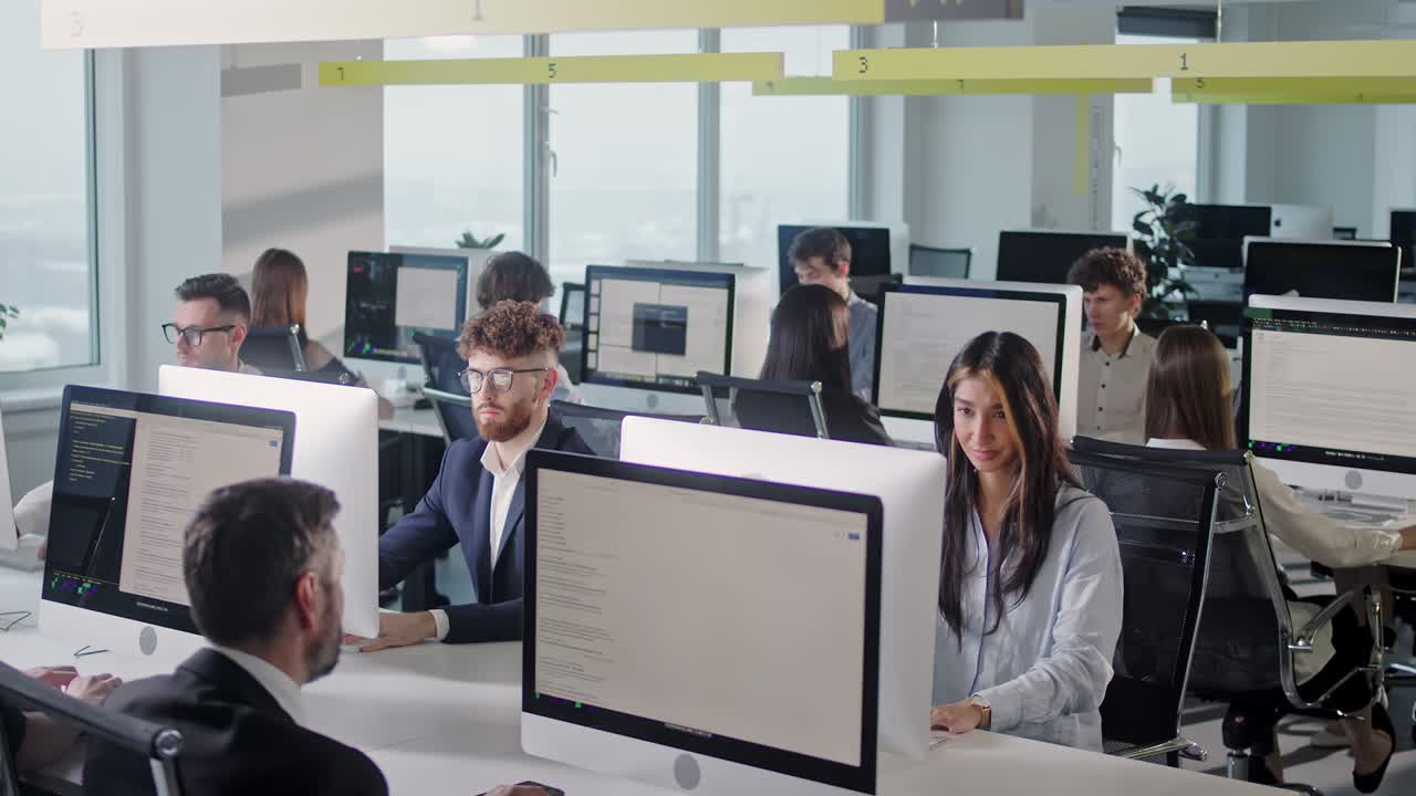 современное открытое пространство корпоративного офиса с мультикультурным занятым персоналом, группа сотрудников, сидящих за компьютерами, сидящими за столами в интерьере рабочей комнаты. позитивное настроение в рабочем коллективе. современный открытый офисный интерьер