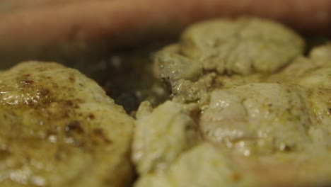 close up view of some smelt cutlets and sausages frying in a pan