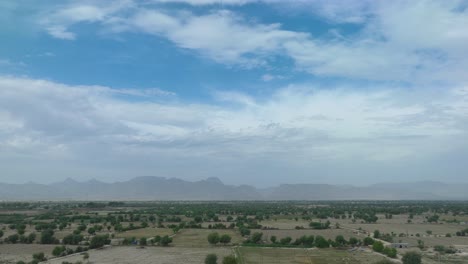 Feld-Mit-Jungem-Grünem-Gras-Vor-Blauem-Himmel-Und-Vorbeiziehenden-Weißen-Wolken