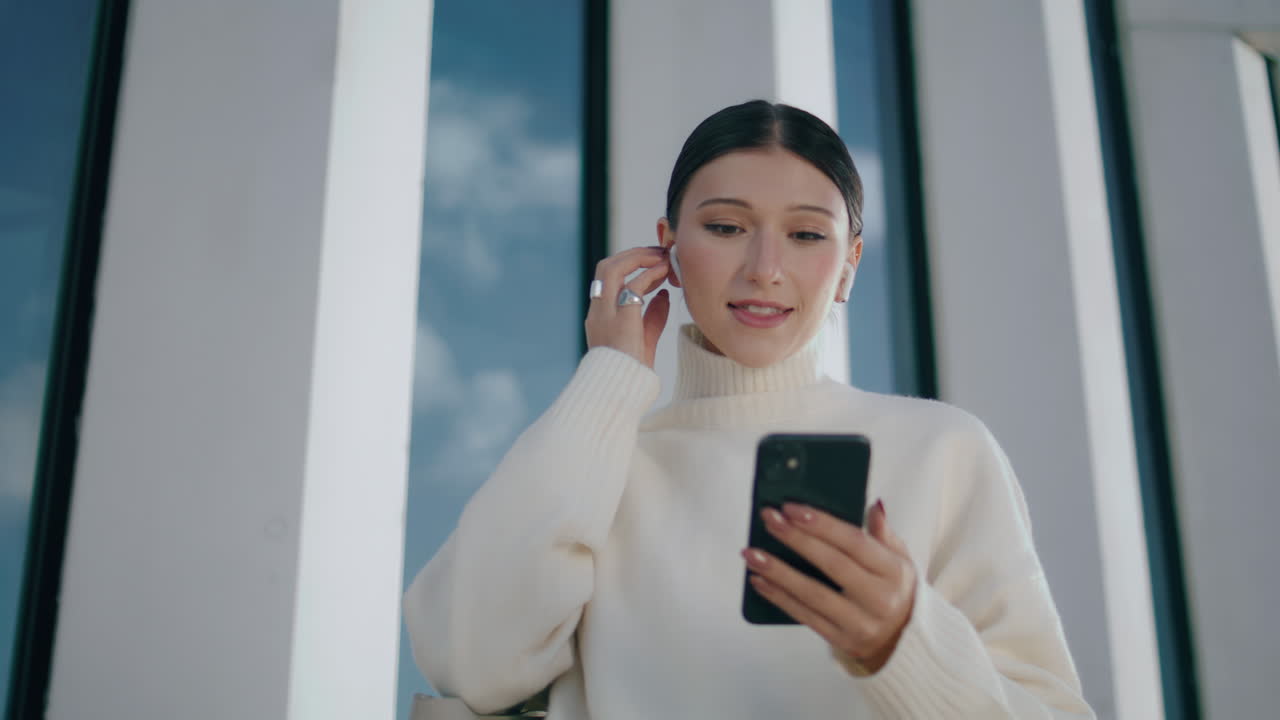 무선 헤드을 착용한 여성이 스마트폰으로 비디오 통화를 하고 있습니다.