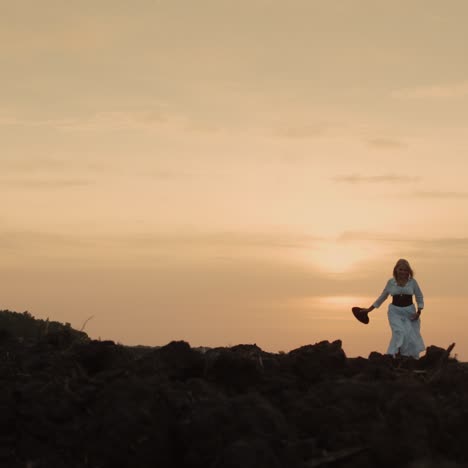 A-woman-in-a-dress-walks-through-a-plowed-field-on-black-soil-1