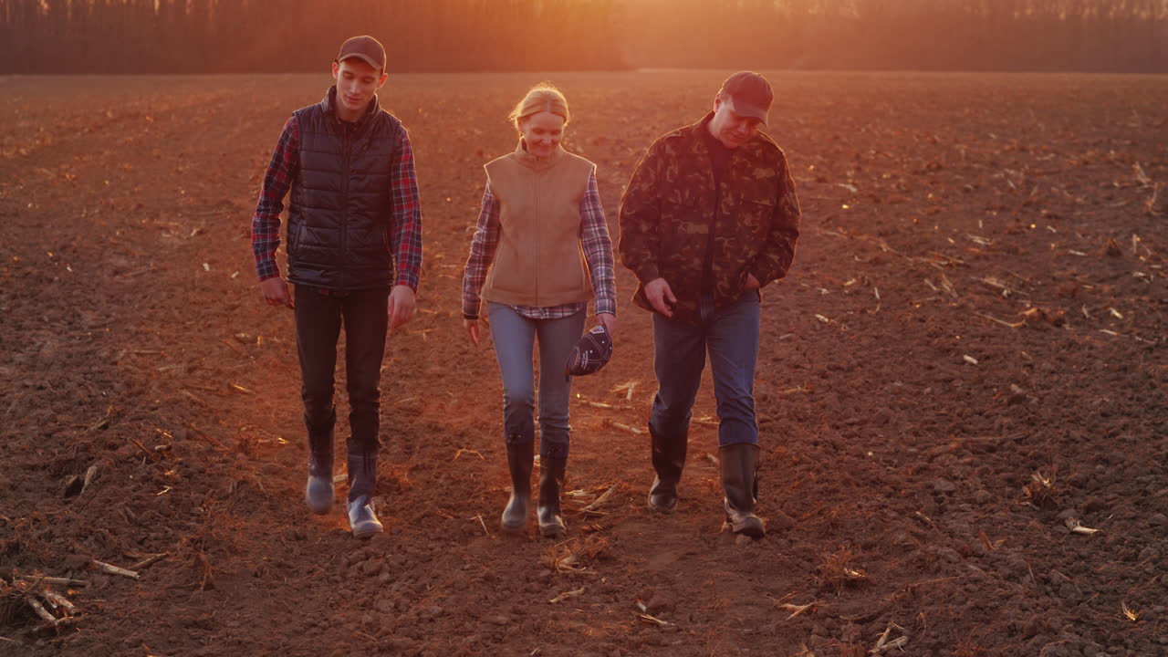 Una famiglia di agricoltori di successo cammina su un campo arato Video 4K