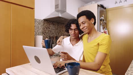 Two men using a laptop in the kitchen