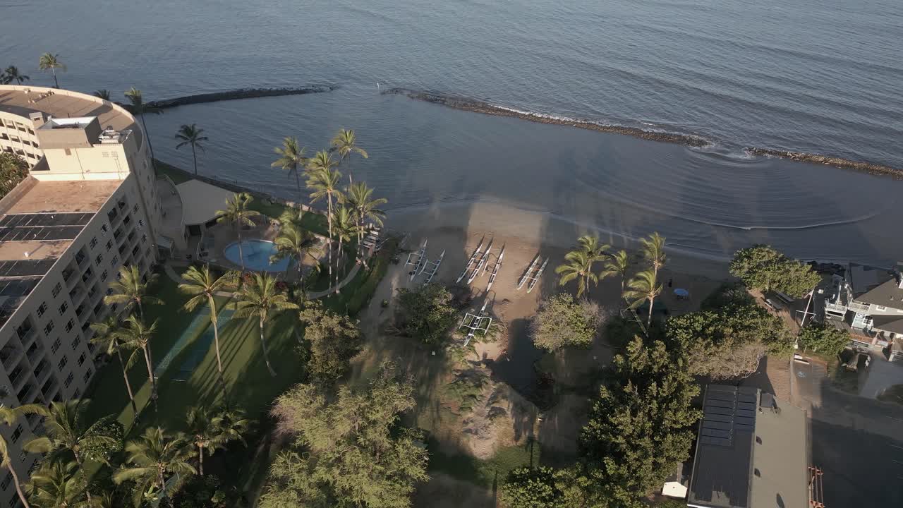 Piroghe polinesiane con bilanciere su una spiaggia sabbiosa delle Hawaii, ripresa aerea in salita.