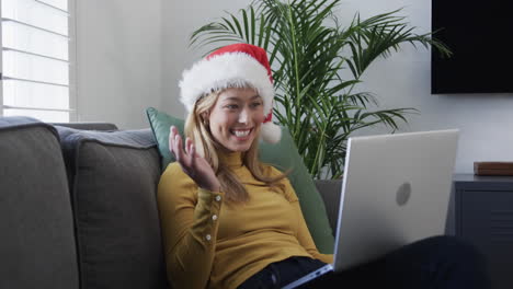 Fröhliche-Biracial-Frau-Mit-Weihnachtsmütze-Und-Laptop-Für-Weihnachtsvideoanruf-In-Zeitlupe