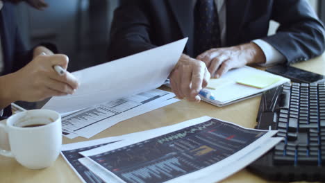 Couple-of-traders-studying-financial-charts-on-papers