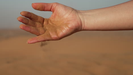 niña vertiendo arena de la mano en el desierto de dubai