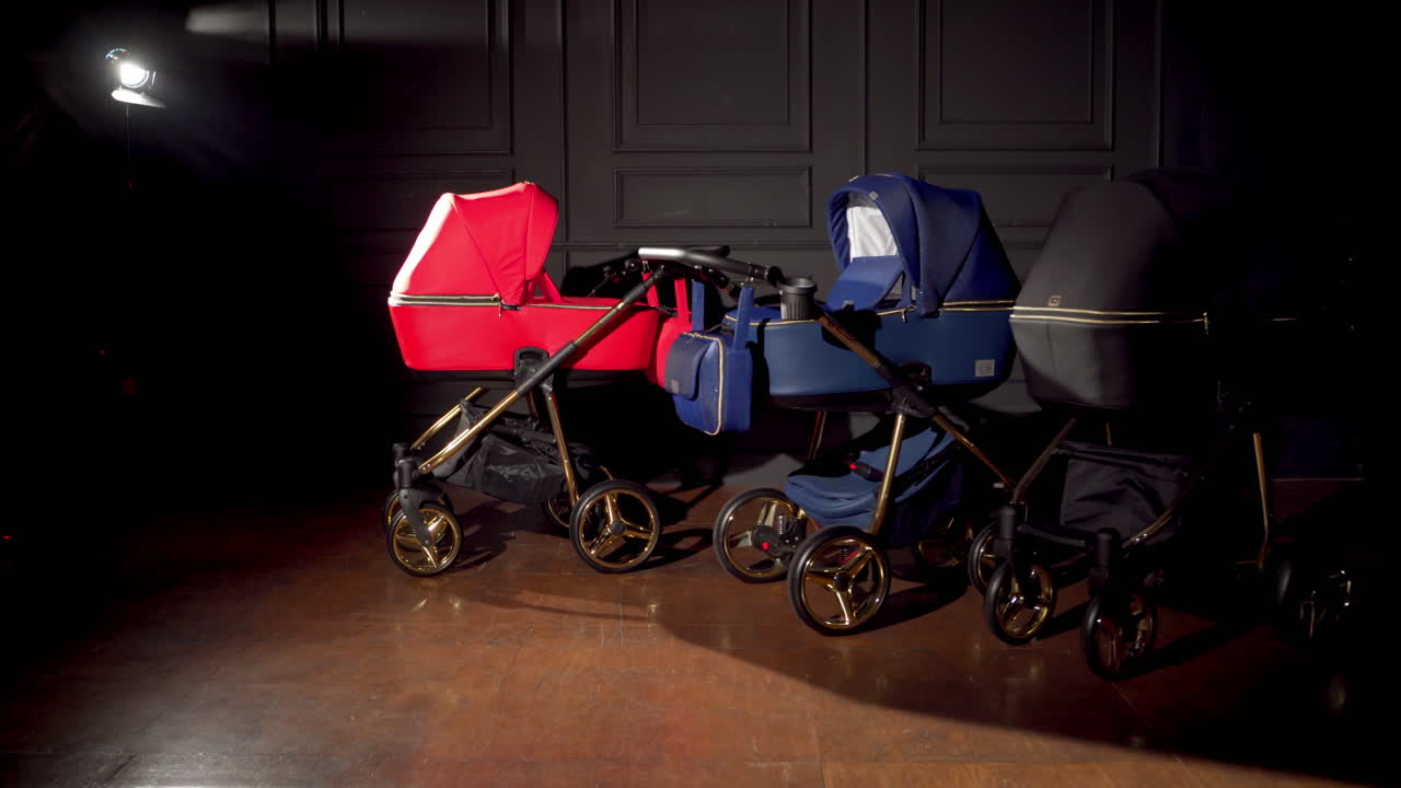 Bright colored baby prams are pushed in the centre of the room. Dark room background.