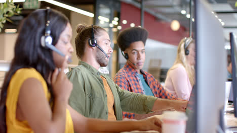 Zufriedene,-Vielfältige-Geschäftskollegen,-Die-Telefon-Headsets-Und-Computer-Verwenden-Und-Im-Büro-Sprechen,-Zeitlupe