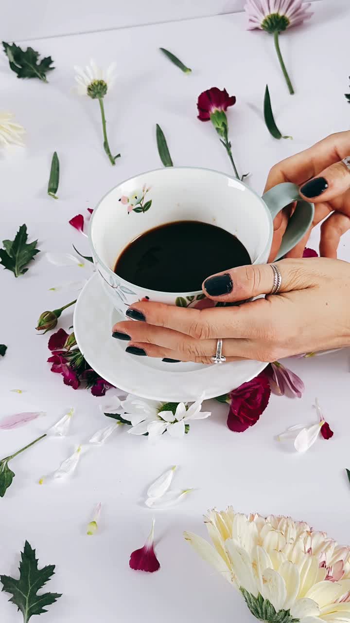 Woman holding a cup of coffee surrounded by flowers