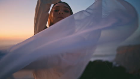 closeup sensual woman moving hands smoothly with fluttering fabric at sunset