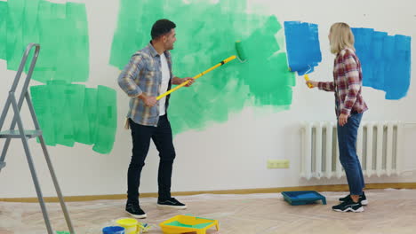 una pareja pintando una pared.