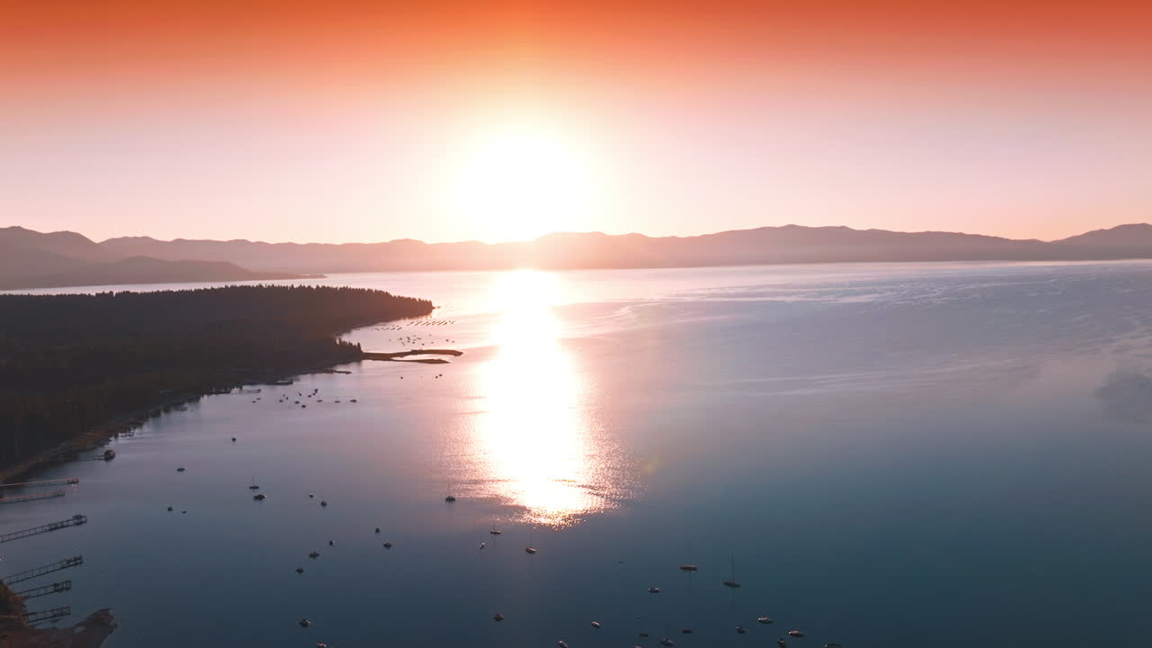 Amazing pink sunset over the lake. Sun reflecting on the smooth surface of water. Multiple boats on water.