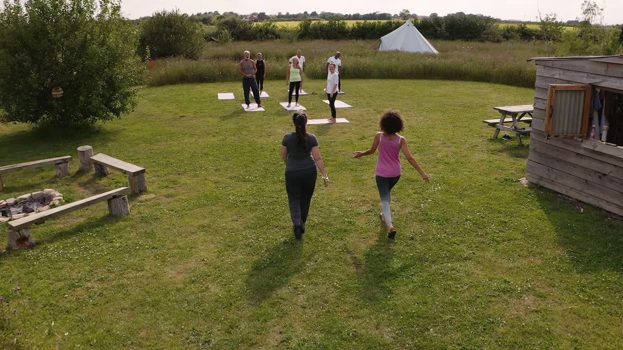 야외 요가 리트리트 에서 성숙 한 남자 와 여자 들 의 그룹 을 이끌고 있는 교사 의 드론  ⁇